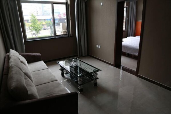 A hotel room with a glass-top coffee table, a sofa, and a bed.