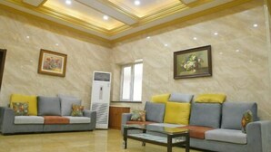 A spacious living room with two sofas, a coffee table, and a large window. - Kingdom Hotel (Panjin)