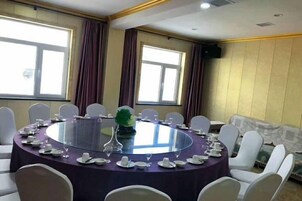A conference room with a round table, white chairs, and a purple tablecloth.