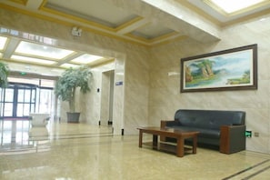 A lobby with a marble floor, a sofa, a coffee table, a potted plant, and a painting on the wall. - Kingdom Hotel (Panjin)