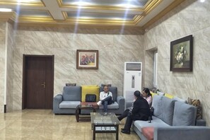 A lobby with a marble floor, a sofa, a coffee table, and a door. - Kingdom Hotel (Panjin)