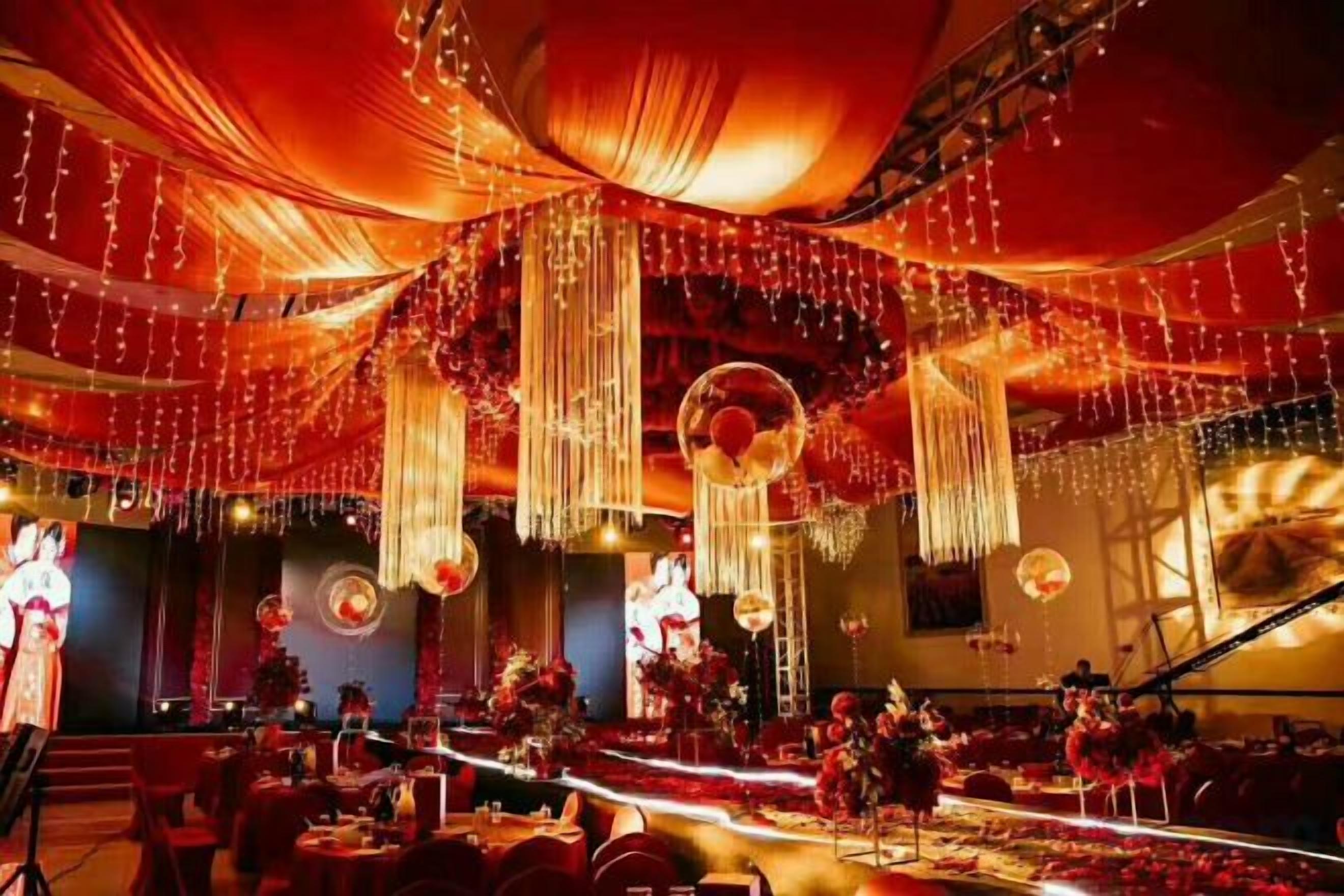 Une salle de banquet équipée d’une scène, de tables et de chaises disposées pour un événement.