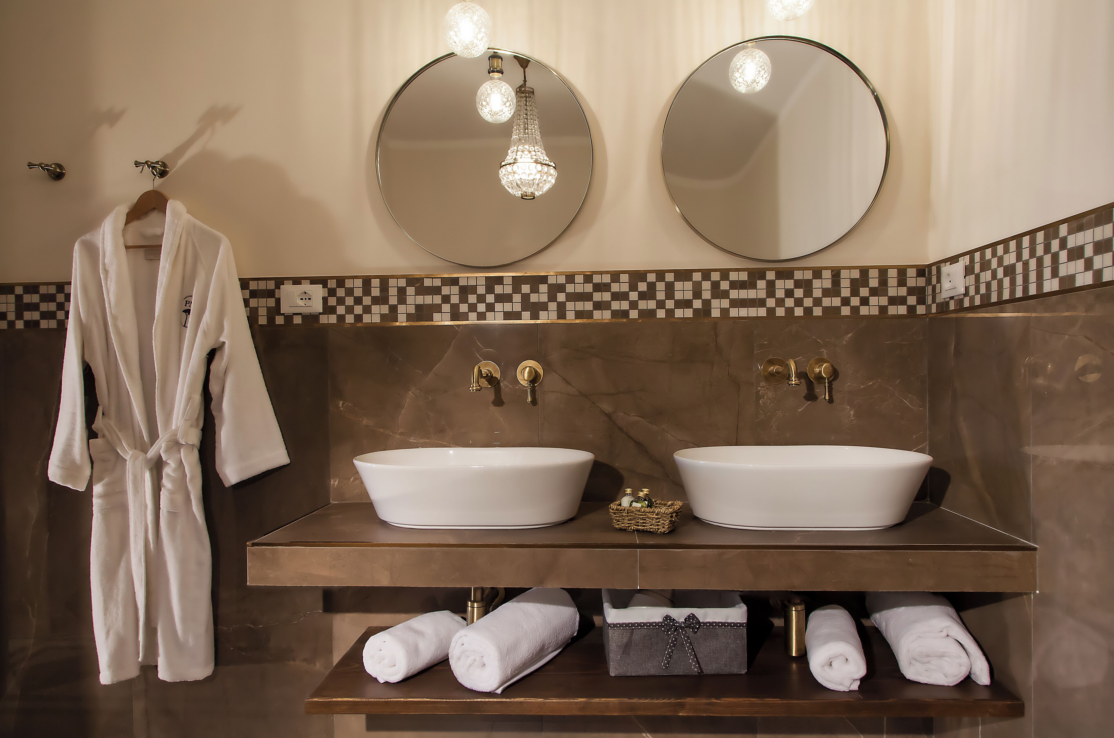 A bathroom with two sinks, a robe rack, and a chandelier.