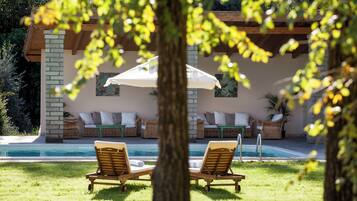 Una piscina al aire libre, sombrillas, sillones reclinables de piscina