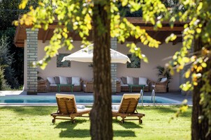 Una piscina al aire libre, sombrillas, tumbonas