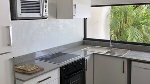 A compact kitchen with white cabinets, a microwave, a stove, and a dishwasher.