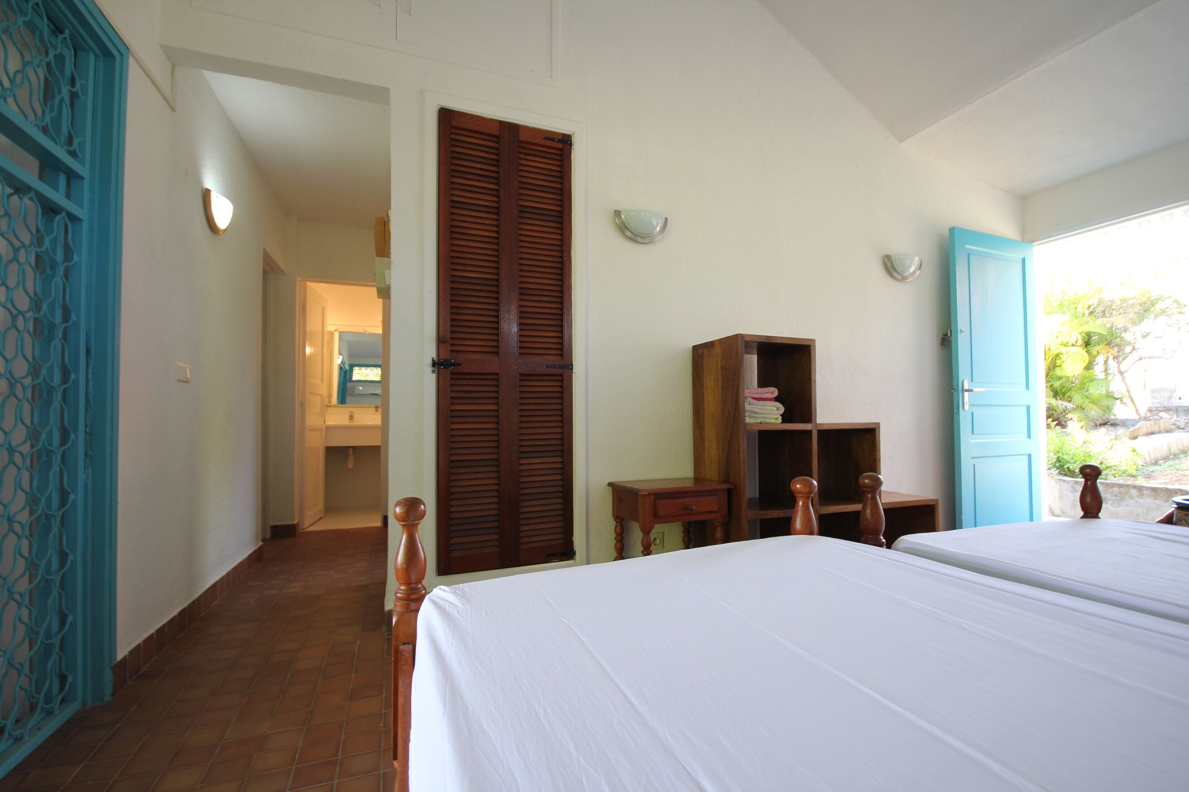 Un dormitorio con dos camas, un armario de madera, una mesita pequeña y una puerta azul.
