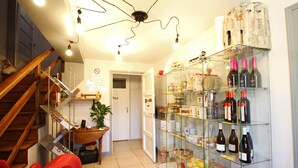 Ein Hotelkorridor mit einer Glasvitrine voller Weinflaschen, einer Holztreppe und einer Tür zu einem anderen Zimmer.