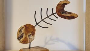 Ein Holzskulptur eines Fischskeletts auf einem Block.