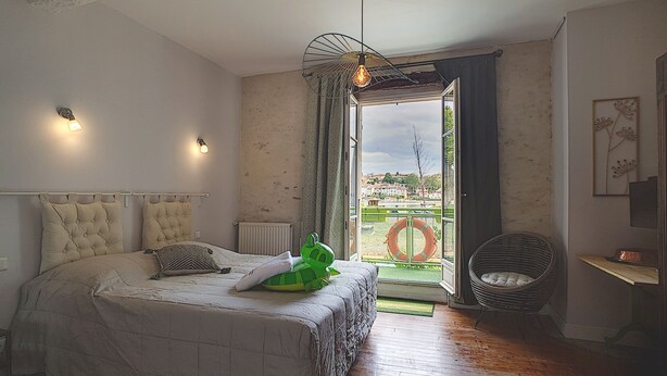 Ein Schlafzimmer mit Bett, Sessel, Heizkörper und Blick ins Freie.