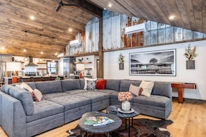 A spacious living area with a large sectional sofa, a coffee table, and a dining table.