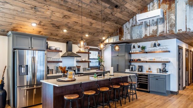 A modern kitchen with a central island, bar stools, stainless steel appliances, and wooden ceiling. - New Rustic Luxe Cabin Billiards Spa Near GSMNP (Townsend)