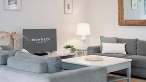 A modern living room with a television, sofa, coffee table, lamp, and framed pictures on the wall. - Alice (Bayona 7) - Little Cove (Noosa Heads)