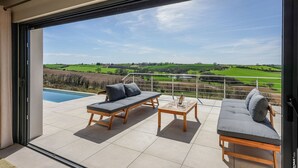 Ein Balkon mit Blick auf eine grüne Landschaft, einen Pool und zwei Sofas.