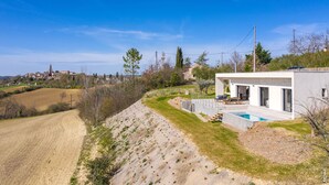 Ein modernes Haus mit Schwimmbad, Terrasse und Blick auf die Landschaft.