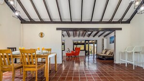 Un vaste espace dédié à la salle à manger, avec une table et des chaises en bois, un canapé rouge et un fauteuil blanc.
