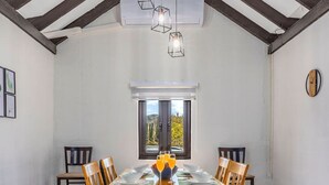 Un coin repas avec une grande table en bois, six chaises et une vue par la fenêtre.