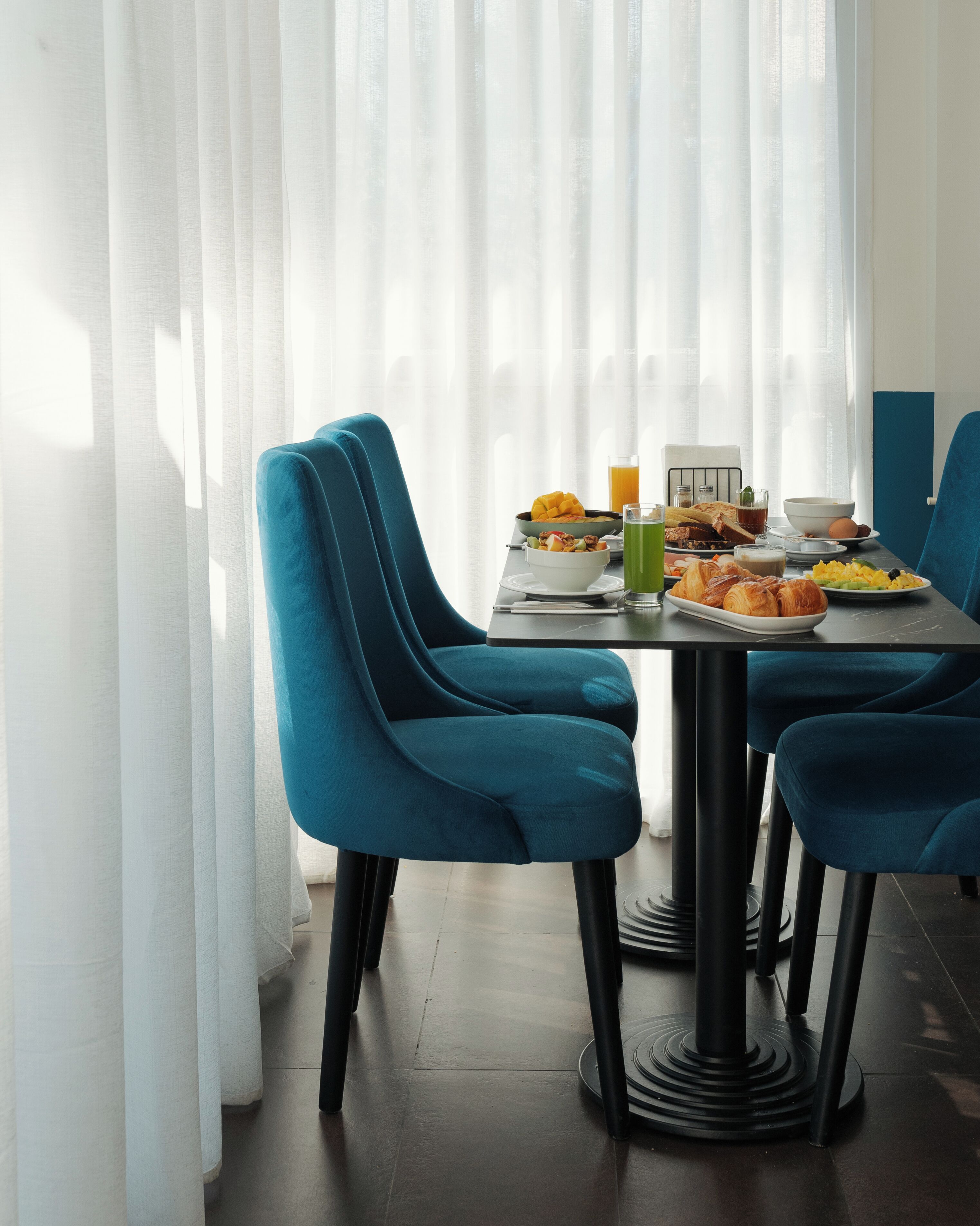 Een eetruimte met een ontbijttafel, belegd met diverse etenswaren en drankjes.