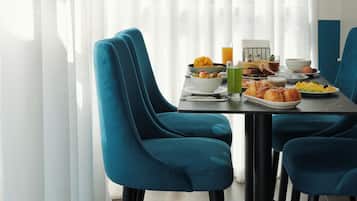 Un coin repas avec une table mise pour le petit-déjeuner, où l'on trouve une variété d'aliments et de boissons.