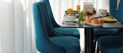 A dining area with a table set for breakfast, featuring a variety of food items and drinks.