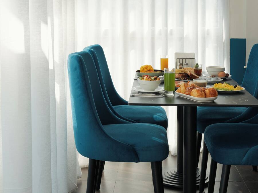 A dining area with a table set for breakfast, featuring a variety of food items and drinks.