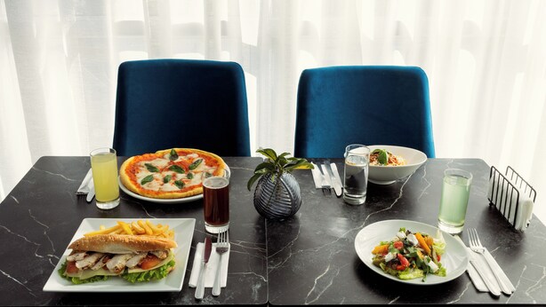 A dining table with a pizza, a sandwich, a salad, and drinks. - Mia Hotels Fes (Fes)