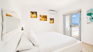 Ein Schlafzimmer mit einem Bett, einem Spiegel, einem Nachttisch und drei Sonnenuntergangsbildern an der Wand.