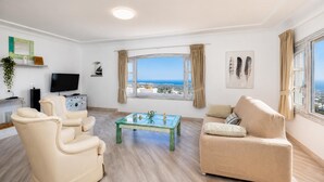 Ein Wohnzimmer mit Sofa, Sessel, Fernseher und einem Tisch mit Dekoration.