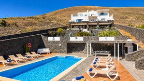 Ein Swimmingpool mit Liegestühlen, ein Grillplatz und ein Gebäude mit Steinverkleidung.