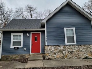 Two-story building with a distinctive architectural style, featuring a red front door and symmetrical windows.