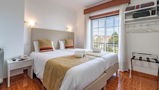 Une chambre d’hôtel avec un grand lit, des tables de chevet, une armoire et une fenêtre donnant sur un beau paysage.