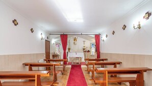 L’intérieur d’une église, avec des bancs en bois, une moquette rouge menant à l’autel et des statues religieuses sur les murs.