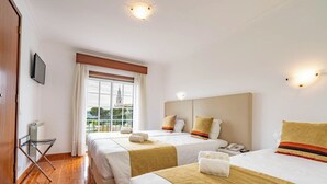 Une chambre d’hôtel avec deux lits, une vue sur une tour depuis la fenêtre et un téléviseur à écran plat fixé au mur.