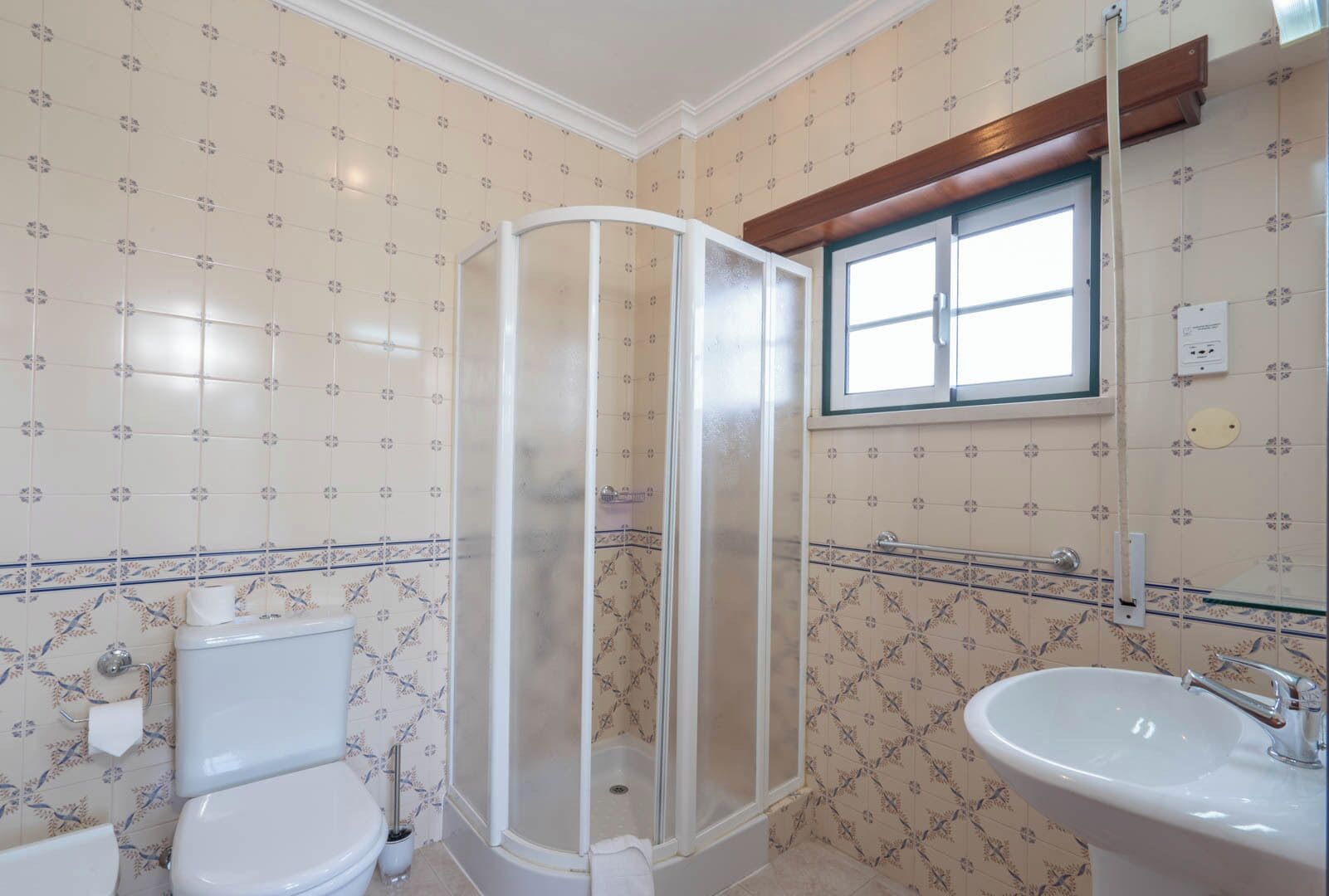 Un baño con inodoro, cabina de ducha y lavamanos.