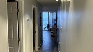 Un couloir doté d’un plancher en bois, de murs blancs et offrant une vue sur l’extérieur.