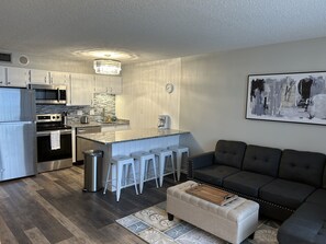 A modern kitchen with stainless steel appliances, a granite countertop, and a bar stool seating area.