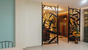 Una habitación con una mesa de comedor, sillas y un separador decorativo con diseños abstractos.