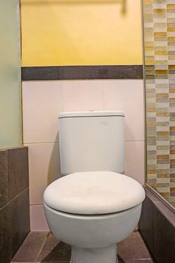 A white toilet in a bathroom with tiled walls and a glass shower enclosure.