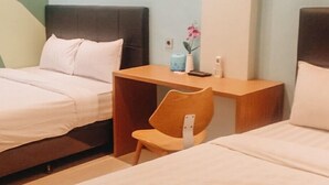 Habitación de hotel con dos camas, una mesita de noche de madera, una silla y una pequeña mesa con un florero.