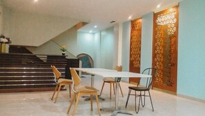 Un comedor con una mesa blanca y cuatro sillas, una escalera de madera y un panel decorativo en la pared.