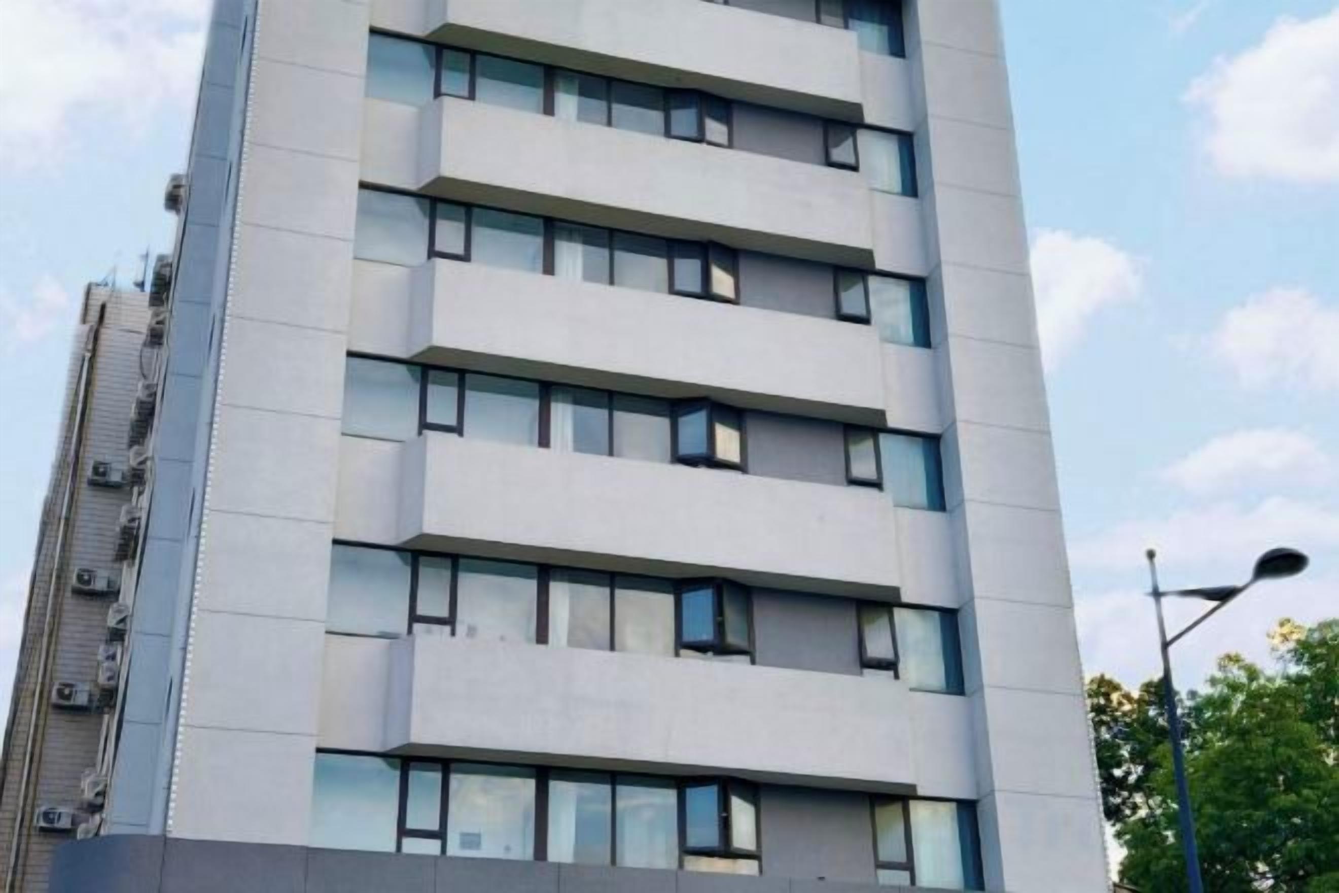 Un edificio de varios pisos con un diseño arquitectónico moderno, que presenta una serie de ventanas en cada nivel.
