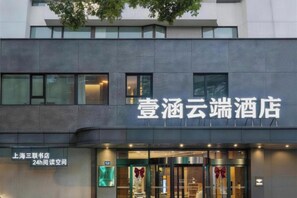 A hotel entrance with a modern facade, a visible entrance door, and a sign indicating a 24-hour reading room. - Yihan Cloud Hotel (Yixing City Center Jiaoq Pedestrian Street Branch) (Yixing)