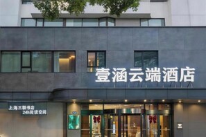 A hotel with a modern facade, a sign indicating 24-hour reading space, and a large entrance with glass doors. - Yihan Cloud Hotel (Yixing City Center Jiaoq Pedestrian Street Branch) (Yixing)