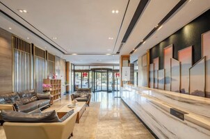 Un vestíbulo de hotel con recepción, zona de estar y vista al acceso.