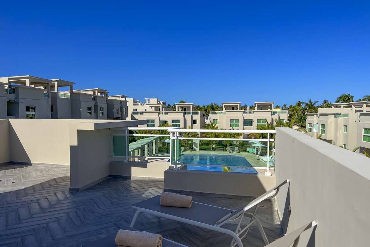 A rooftop terrace with a pool, lounge chairs, and a clear view of the surrounding buildings.