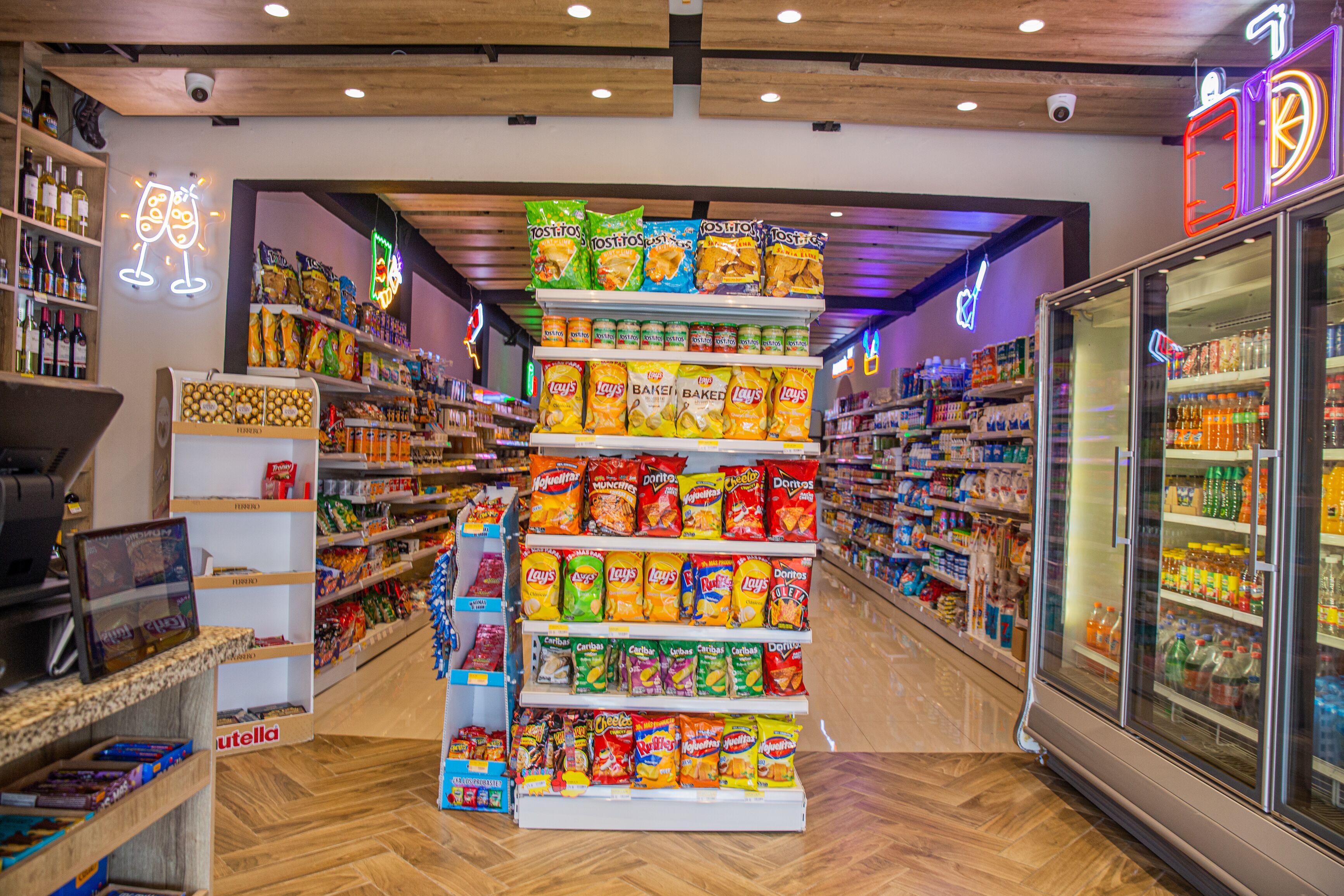 A grocery store with shelves stocked with snacks and beverages, a refrigerated section, and a checkout area.
