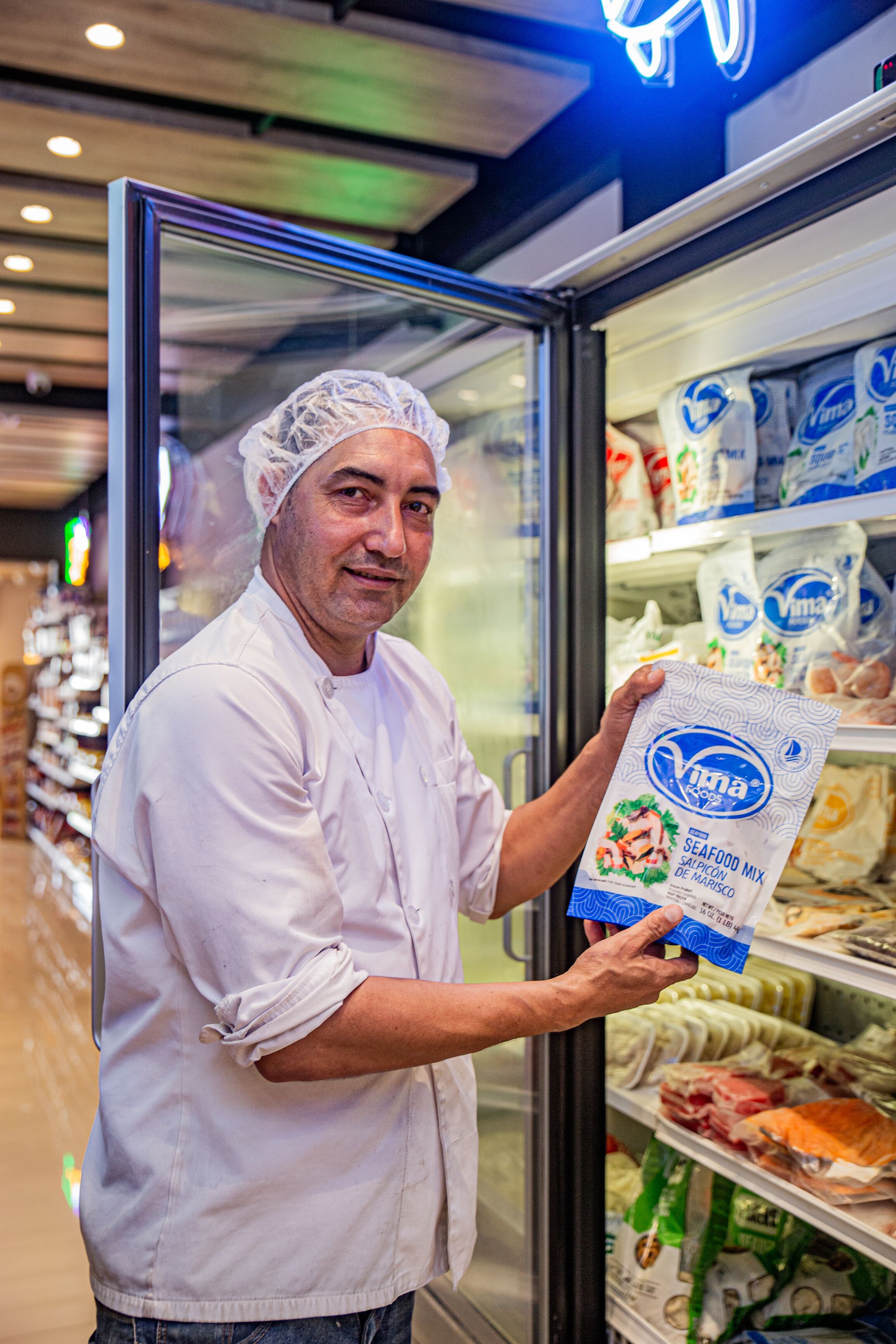 A person in a white chef's uniform holding a bag of seafood mix.