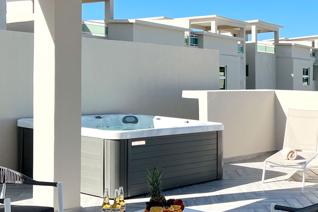 Une terrasse sur le toit avec un jacuzzi, des sièges d’extérieur et une table où sont servis des boissons et des fruits.