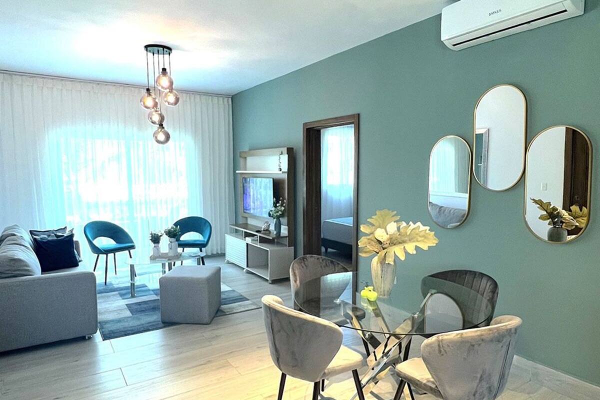 A modern living room with a sofa, chairs, a TV, and a dining table.