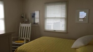 A bedroom with a bed, a chair, a window with blinds, and a wall-mounted picture. - Sought after LEYC oceanfront (Beach Haven)